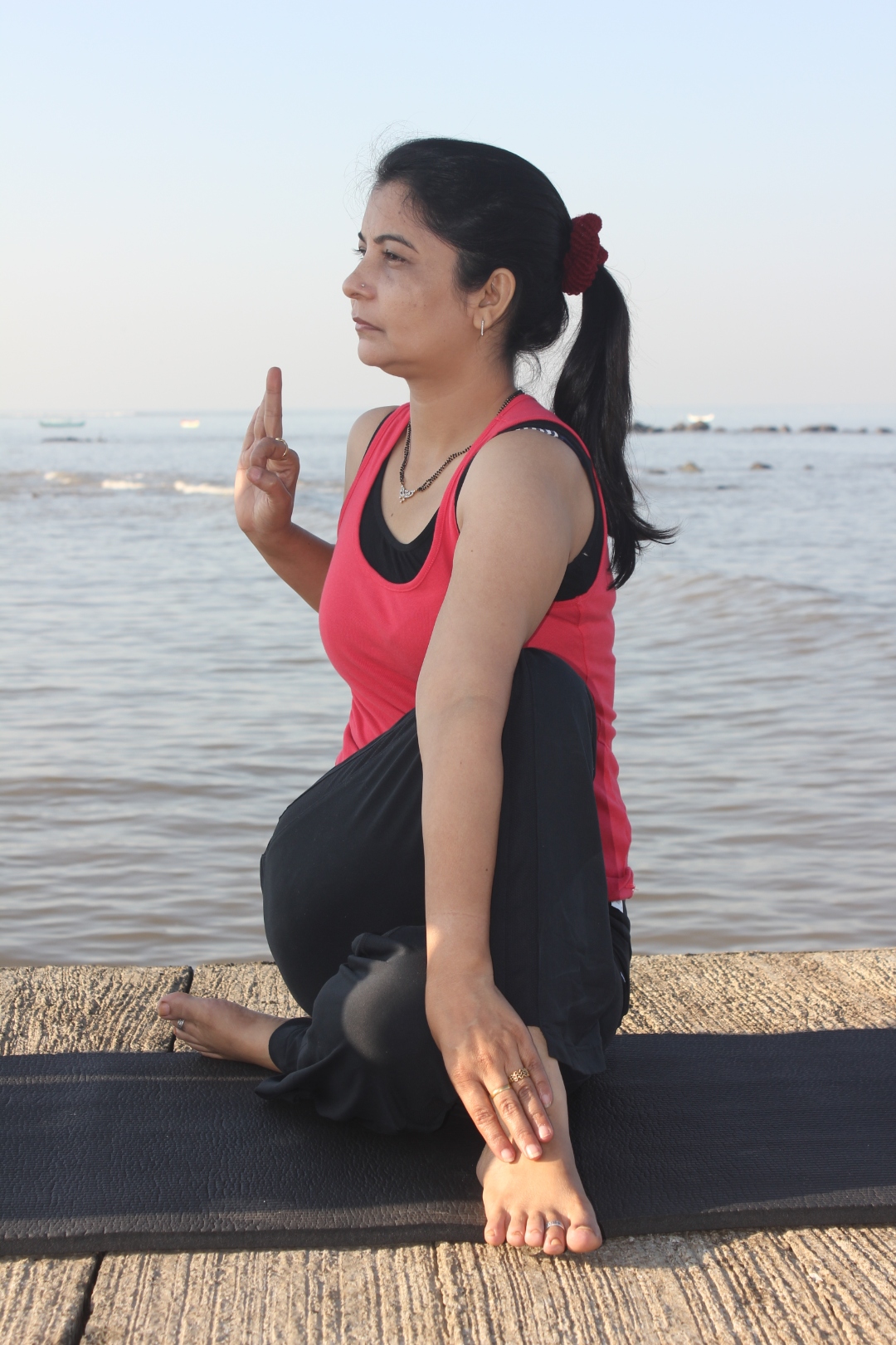 Kamini Sharma in a seated yoga twist by the sea